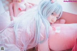 A woman sitting on a bed with a pink stuffed animal.
