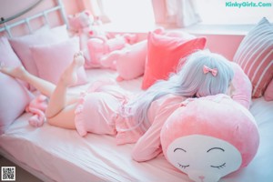 A woman sitting on a bed with pink stuffed animals.