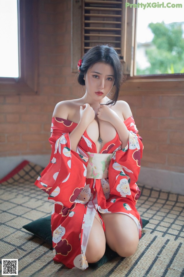 A woman in a red kimono sitting on the floor.