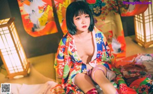 A woman in a colorful kimono sitting on the floor.