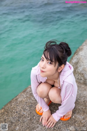 A woman crouching down with a flower in her hand.