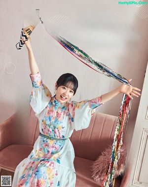 A woman in a blue dress holding up a paper cone.