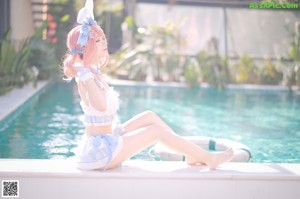 A woman in a bunny costume sitting by a pool.