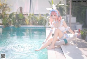 A woman in a bunny costume posing by a pool.