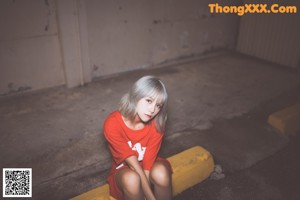 A young girl in a red shirt behind a chain link fence.