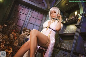 A woman in a white dress sitting on the floor.