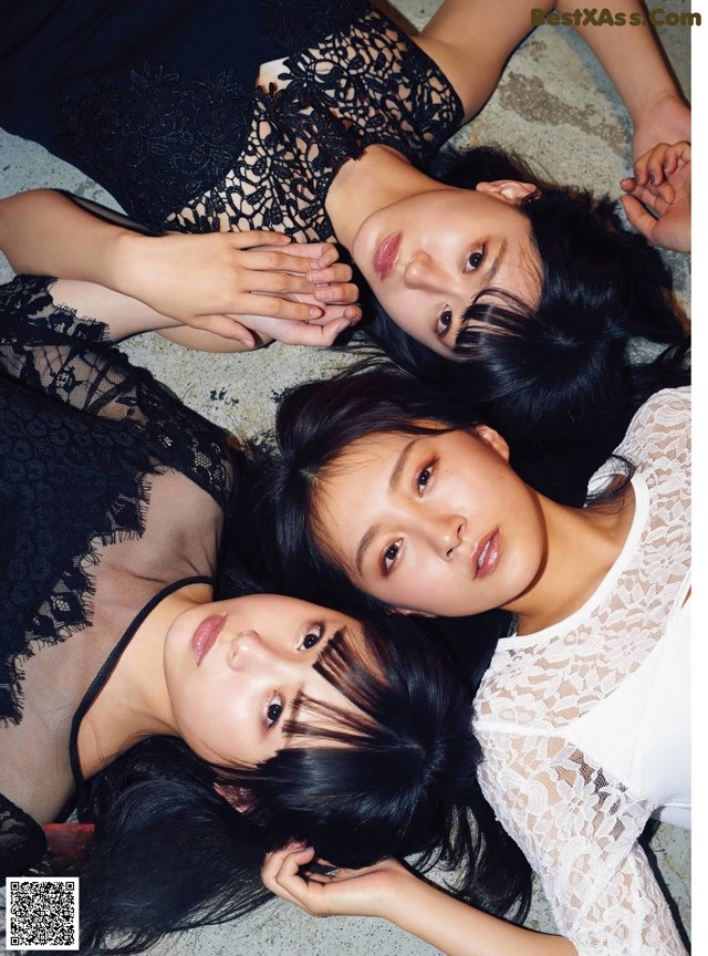 A group of three young women laying on the ground.