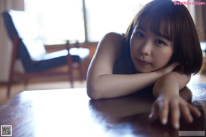 A woman in a gray top and blue panties sitting on the floor.