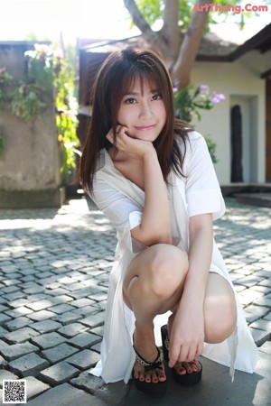 A woman sitting on a wooden deck with her legs crossed.