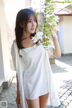 A young woman leaning against a bamboo fence.