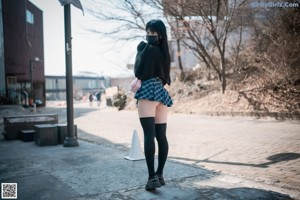 A woman in a skirt and stockings posing for a picture.