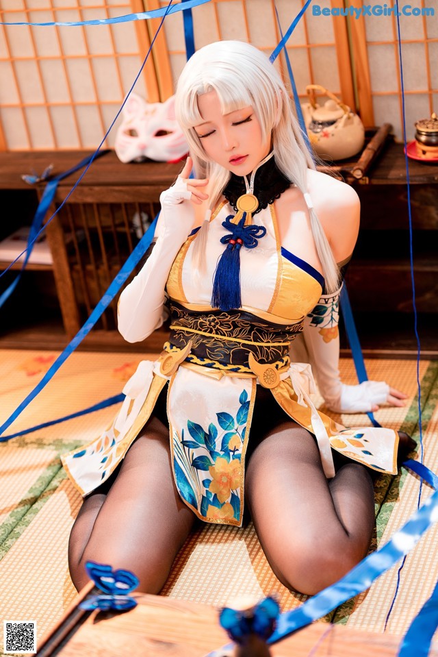 A woman in a blue and yellow outfit sitting on the floor.