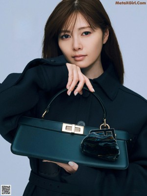 A woman in a black suit holding a red handbag.