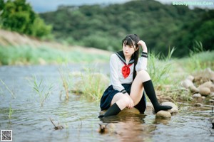 A woman in a white shirt and black skirt is sitting in the water.