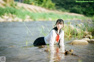 A woman in a sailor outfit sitting in the water.