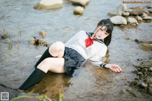 A woman in a school uniform standing in the water.