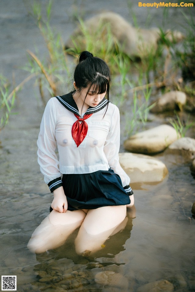 A woman in a sailor outfit sitting in the water.