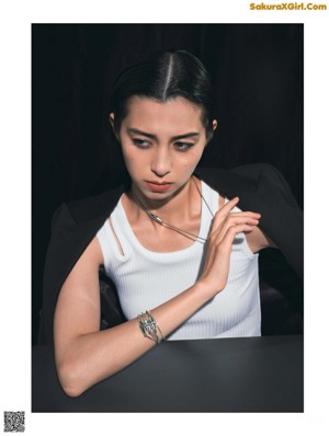A woman wearing a black sweater and gold rings.