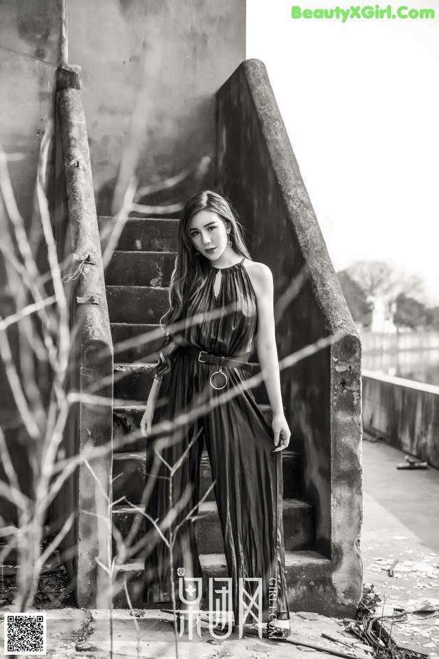 A woman in a black dress standing on some steps.