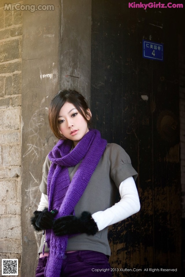 A woman wearing a purple scarf and black gloves.