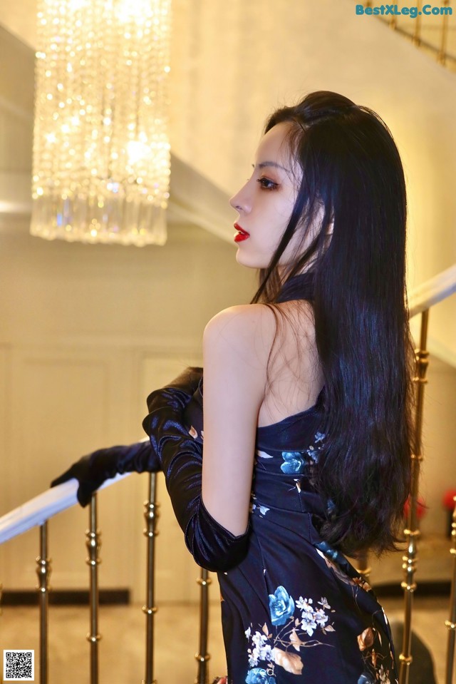 A woman in a black dress and gloves standing on a staircase.