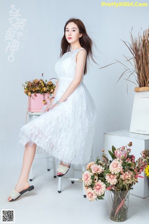 A woman sitting on a chair surrounded by flowers.