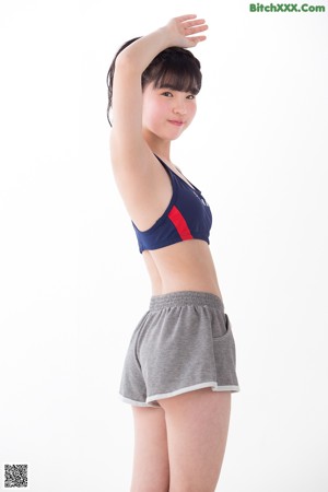 A woman in a sports bra top and shorts posing for a picture.