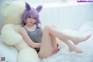 A woman in a purple lingerie sitting on a bed.