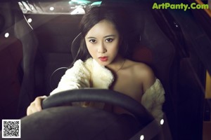 A woman sitting on top of a yellow sports car.