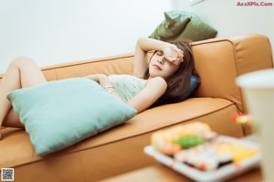 A woman sitting on a couch holding a bag of chips.