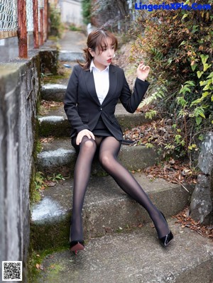 A woman in a black dress and red high heels posing for a picture.