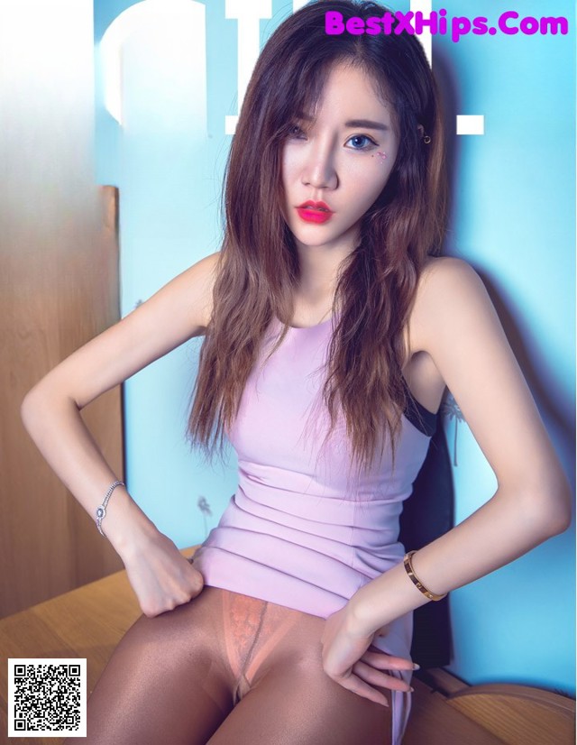 A woman in a pink tank top and pantyhose posing for a magazine cover.