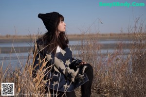 A woman sitting on the ground next to a car.