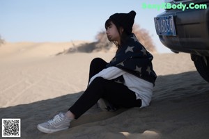 A woman laying on the sand under a blanket.