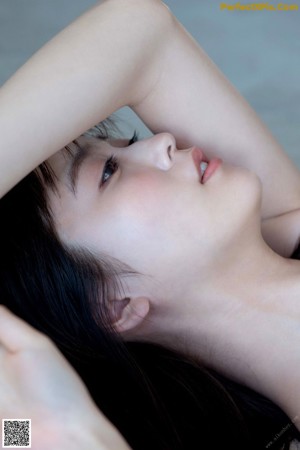 A naked woman sitting on the floor with her legs crossed.
