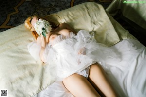 A woman in a white lingerie sitting on a bed.