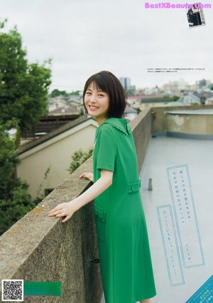 A woman in a pink dress standing in front of a white brick wall.