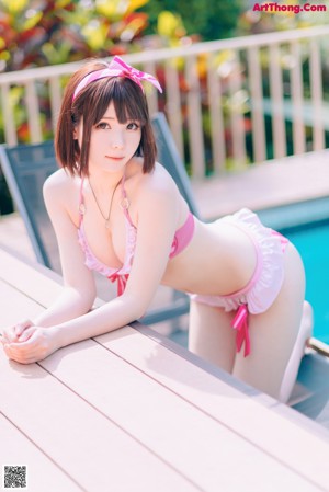 A woman in a pink bikini sitting on a wooden bench.