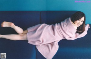 A woman laying on a bed with her legs up.