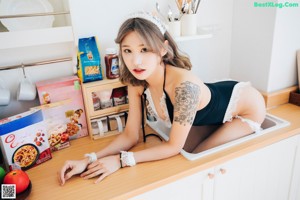 A woman in a black and white lingerie sitting on a bed.