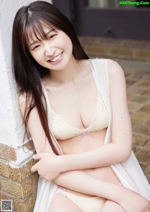 A woman in a yellow bra and panties leaning against a window.