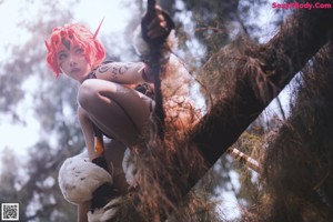 A woman with red hair sitting on a tree branch.