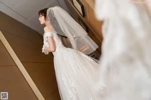 A woman in a wedding dress making a heart with her hands.