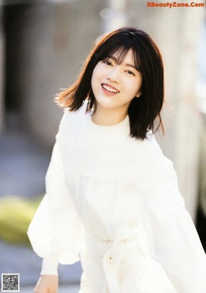A woman in a white dress is posing for a picture.