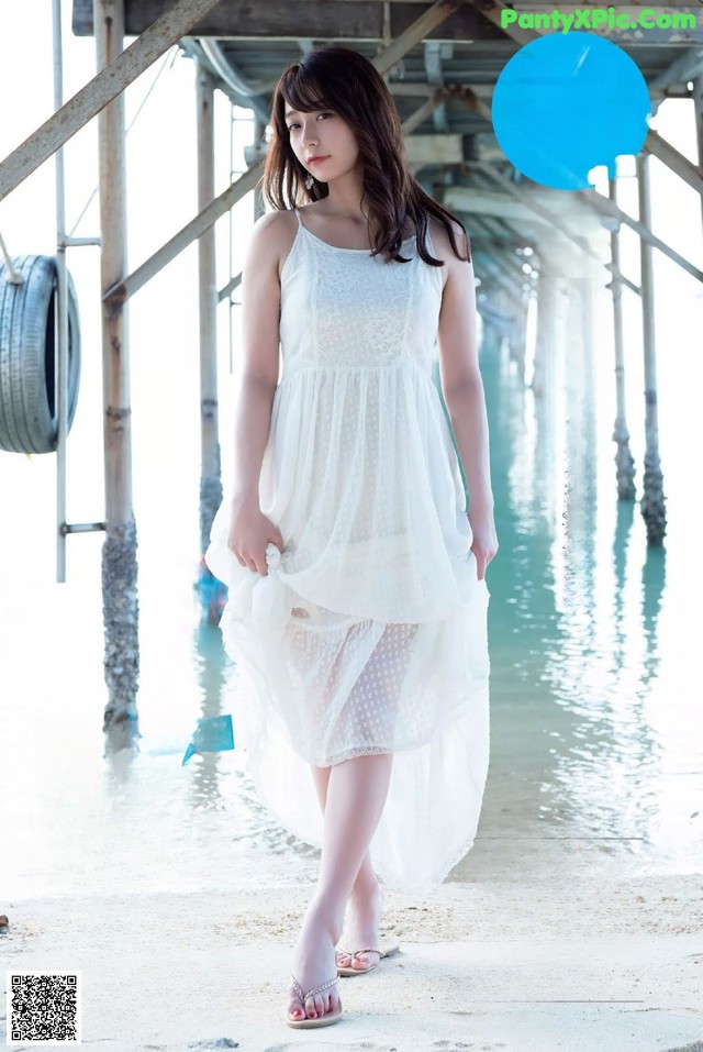 A woman in a white dress standing on a pier.