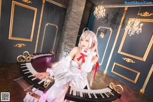 A woman in a white dress sitting on a piano.