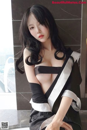 A woman in a black and white robe sitting on a bathtub.
